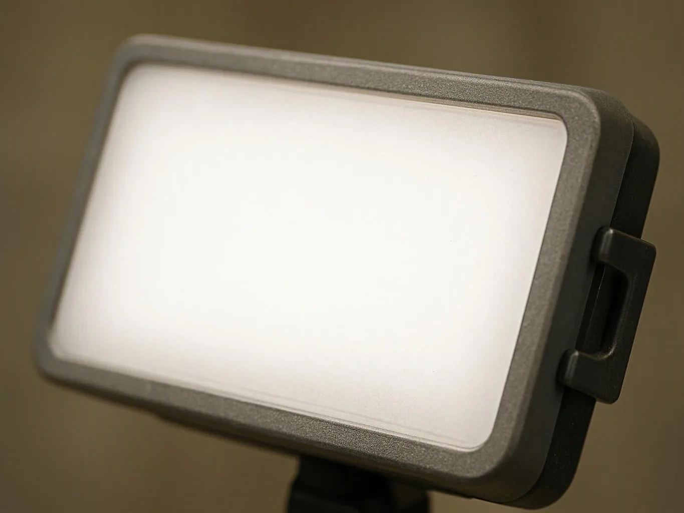 A blank rectangular LED panel light sits on a stand against a soft brown background