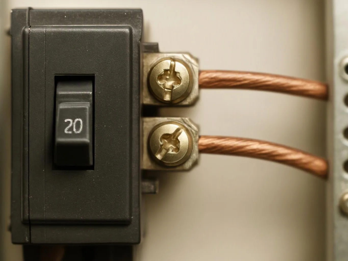 Close-up of a black 20 amp breaker with two copper wires attached to brass terminals